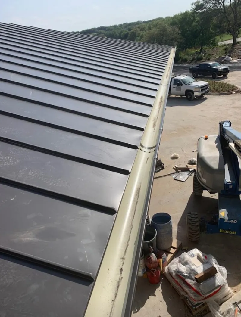 Standing seam panel and gutter detail on a metal roofing jobsite in Girard